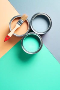 Metal paint cans and paint brushes on multicolor background. Top view. Copy space. Trendy green color concept