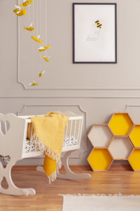 Cot with a blanket and yellow honeycombs in a kid room interior. Real photo
